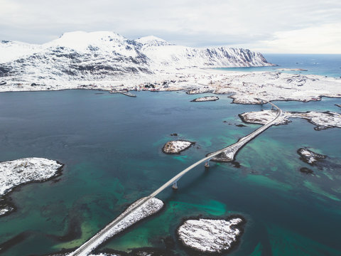 Aerial winter view of Lofoten Islands, Nordland, Norway, with fjord, road, bridge and mountains, shot from drone