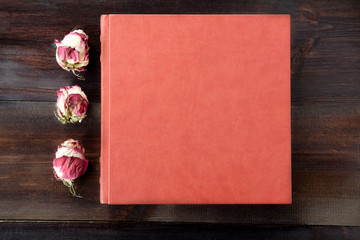 Brown wedding album with rose flowers decoration on brown wooden background