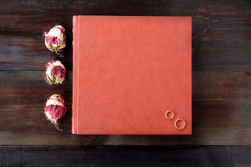 Brown wedding album with rose flowers decoration on brown wooden background