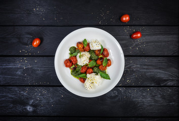 Mozzarella with grilled cherry tomatoes, pesto sauce and basil.
