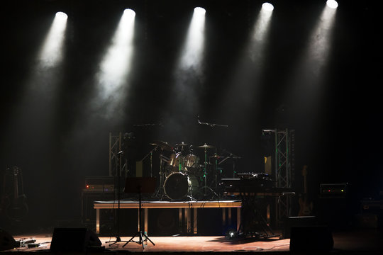 Stage before the concert with drums, guitars and amplifiers lit by spotlights