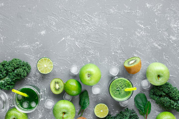 Healthy green smoothie with fresh green fruits, kale and spinach on gray background, with copy space