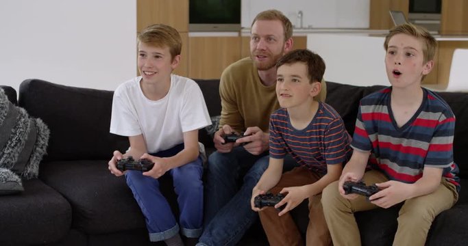 Handsome man and three children play on games console in contemporary modern home and nearly score, in slow motion