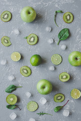 Fresh green fruits, kale and spinach on gray background with copy space, top view