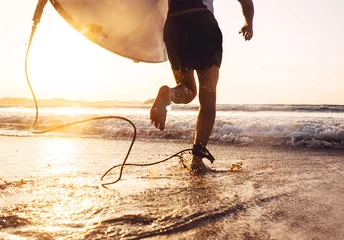 Fotobehang Man surfer rennen in de oceaan met surfplank. Actieve vakantie, gezondheidslevensstijl en sportconceptbeeld © Soloviova Liudmyla