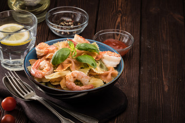 Delicious farfalle pasta with shrimps on wooden background. Mediterranean cuisine