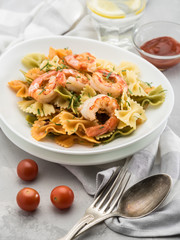 Delicious farfalle pasta with shrimps on the white table. Mediterranean cuisine