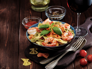 Delicious farfalle pasta with shrimps on wooden background. Mediterranean cuisine