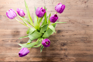 Ein Strauß mit Lila Tulpen auf einem Holztisch