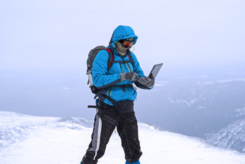 climber working with a laptop in winter on top of a mountain in extreme conditions