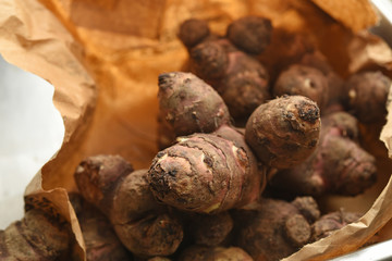 Fresh raw Jerusalem artichoke or topinambur in a paper bag