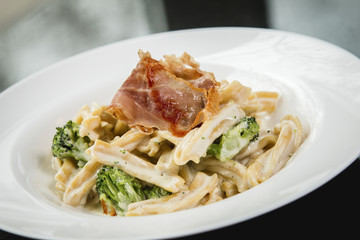 Close up of an Alfredo homemade pasta with crispy bacon and broccoli
