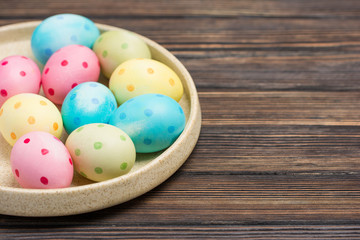 Rustic still life -  Colorful polka dot eggs on plate on wood background, close-up with place for...