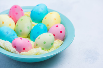 Happy Easter concept. Trendy hand made Colorful polka dot eggs in cup on concrete light grey background.