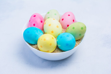 Happy Easter concept. Trendy hand made Colorful polka dot eggs in cup on concrete light grey background.