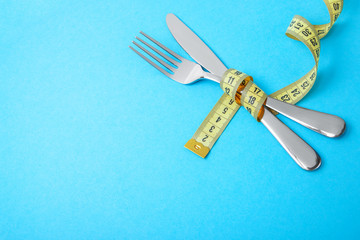 Hunger strike as way to lose weight. The fork and knife are wrapped in yellow measuring tape on...