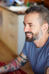 Obraz premium Mid 30's caucasian man with beard and blue shirt smiling sit at the table.