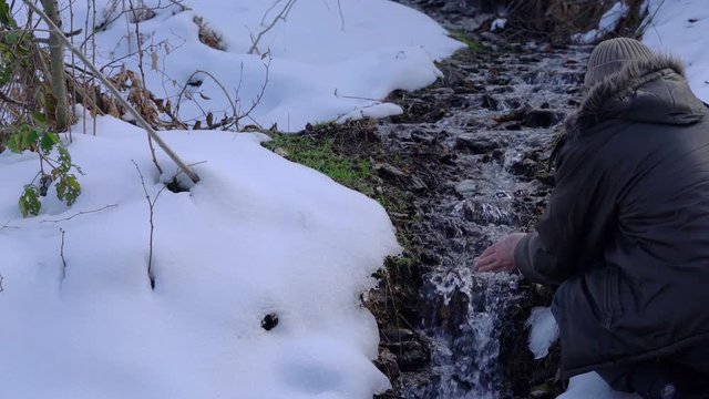 Man washes his hands in a forest creek - (4K)