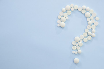 Concept medical of exam, diagnosis and treatment, on blue background with mix pills as question mark