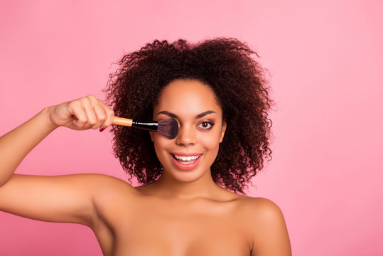 Portrait of pretty, cheerful, nude, natural, charming, attractive, cute, playful, cute, sexy, lovely girl covering, closing her one eye with brush, wellness, wellbeing, isolated over pink background