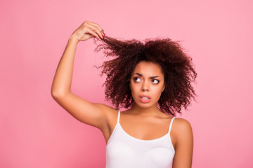 Fototapeta Portrait of pretty, worry, attractive girl examine, look her curly hair, holding strand with hand, she want straight perfect, soft, shine hair, need treatment and therapy  isolated on pink background obraz