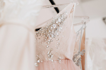 close-up embroidered with stones and sequins top pink wedding dress which hangs on a hanger among other dresses