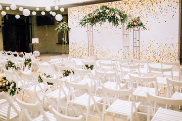 wedding arch decorated with glass balls and white chairs decorated with flowers, spruce and cloth