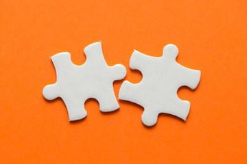Obraz premium Two white details of puzzle on orange background