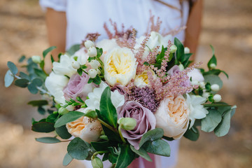 Bride in white dress holding bouquet of flowers in the forest