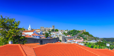 Obraz premium View of the beautiful medieval historic center village of Obidos and Castle of Obidos. Wonderful romantic afternoon landscape at sunny weather. District of Leiria, in the centre of Portugal.