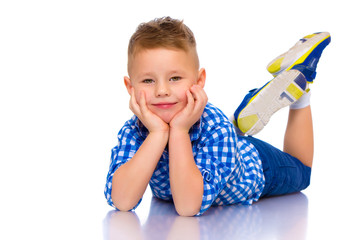 Happy little boy is lying on the floor in the studio.