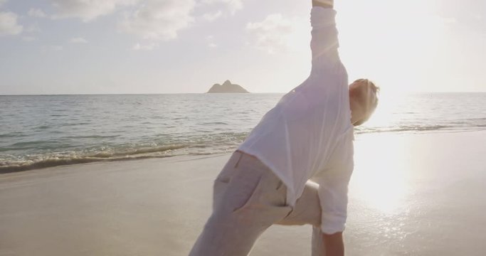 Yoga class. Yoga and meditation People pose at beach at sunrise. Man wan woman doing yoga woking out training in serene ocean nature doing Extended Side Angle Pose. RED EPIC SLOW MOTION STEADICAM