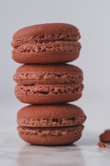 Fototapeta na wymiar Red macarons arranged one over another on white marble background. Close up.