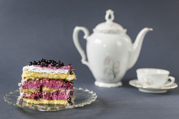 Piece of blueberry cake with cup of tea on blue background