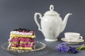 Piece of blueberry cake with cup of tea on blue background