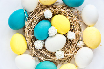 Fototapeta na wymiar colored blue and yellow Easter eggs in nest on wooden background, selective focus image. Happy Easter card 