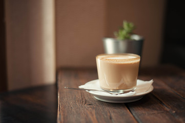Delicious cappuccino and saucer are on a wooden table in the cafe