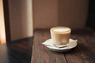 Delicious coffee drink and saucer are on a wooden table in the cafe