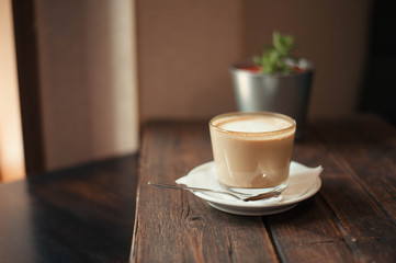 Delicious coffee drink and saucer are on a wooden table in the cafe