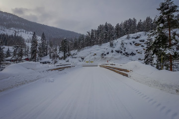 Outdoor view of winter road snow and ice in the forest of Norway