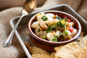 Ensalada y Late Camaron Peruvian Shrimp Salad with Tortilla Chips plated on a tray on burlap and...