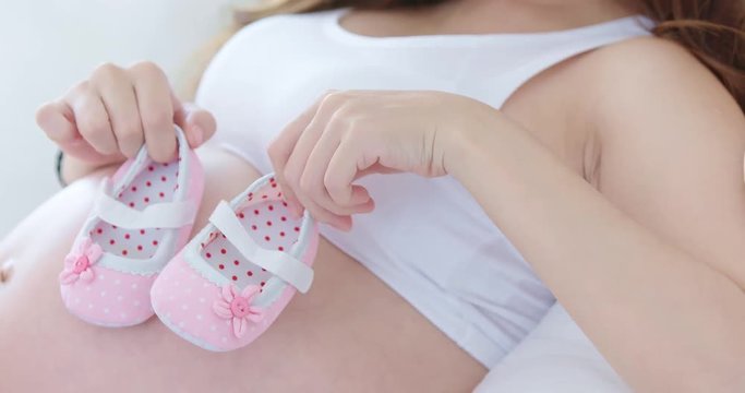 pregnant woman holding baby shoes