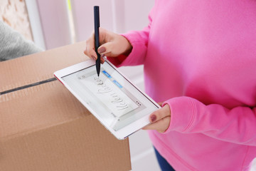 Woman signing on tablet for parcel delivery, closeup