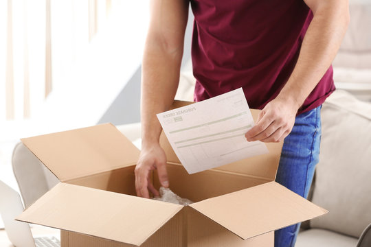 Young man unpacking parcel at home