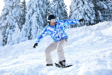 Fototapeta na wymiar Snowboarder on ski piste at snowy resort. Winter vacation
