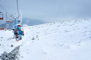 Fototapeta na wymiar Couple on ski lift at mountain resort. Winter vacation