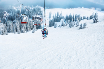 Fototapeta na wymiar Couple on ski lift at mountain resort. Winter vacation
