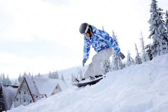 Snowboarder on ski piste at snowy resort. Winter vacation