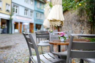 Empty outdoor cafe on beautiful rainy autumn day in Lindau, Germany. Empty chiars and tables under...