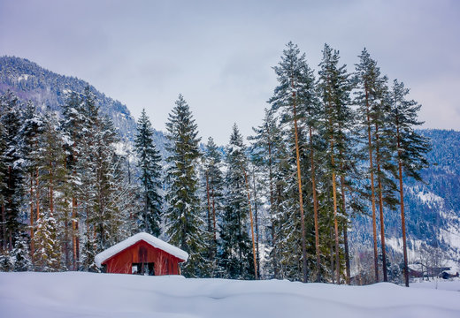 Astonishing outdoor view of traditional Norwegian mountain red houses of wood covered with snow in the roof in stunning nature background in Norway